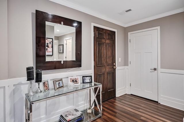 entryway with dark wood finished floors, crown molding, visible vents, and wainscoting