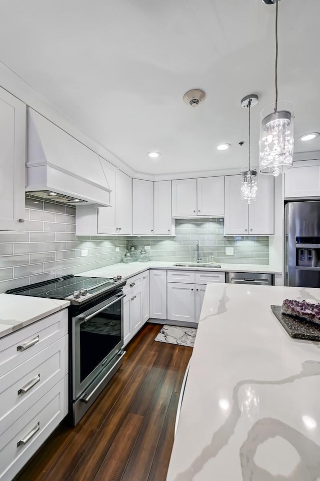 kitchen with white cabinetry, stainless steel appliances, dark hardwood / wood-style floors, decorative light fixtures, and custom range hood