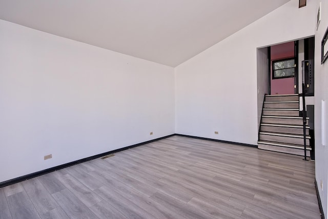 empty room with light hardwood / wood-style flooring and lofted ceiling