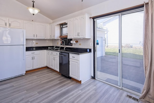 kitchen featuring white cabinetry, dishwasher, white fridge, and lofted ceiling