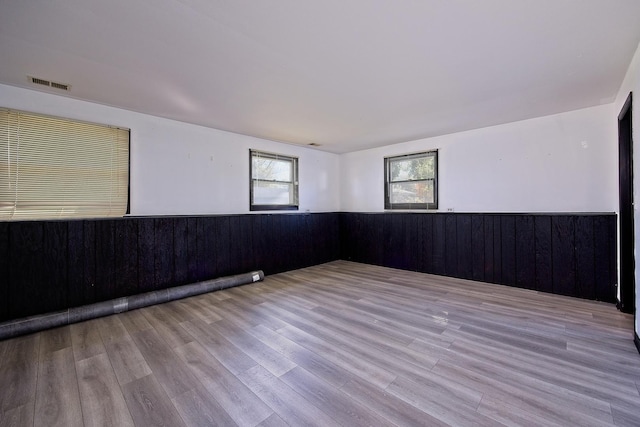 empty room with wooden walls and light hardwood / wood-style flooring