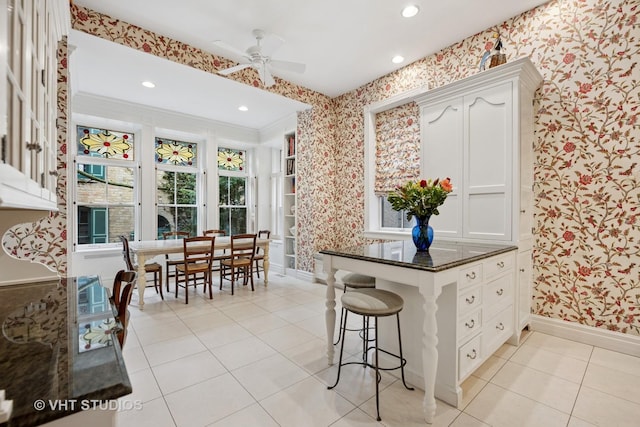 kitchen featuring a ceiling fan, wallpapered walls, light tile patterned flooring, and baseboards