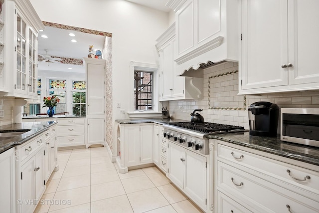 kitchen with backsplash, white cabinets, light tile patterned flooring, and appliances with stainless steel finishes
