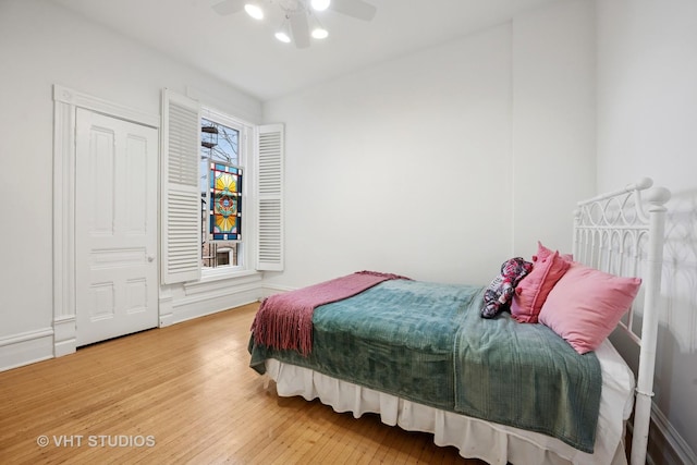 bedroom featuring baseboards, wood finished floors, and a ceiling fan