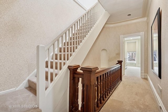 staircase with wallpapered walls, ornamental molding, carpet, and baseboards