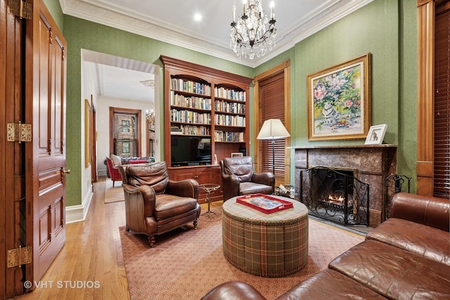 sitting room with a chandelier, light wood finished floors, a fireplace, baseboards, and ornamental molding