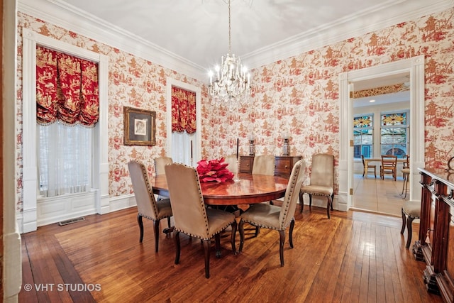 dining space with wallpapered walls, visible vents, hardwood / wood-style flooring, and an inviting chandelier