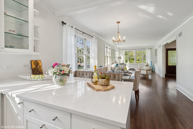 kitchen with white cabinetry, crown molding, light stone counters, and decorative light fixtures