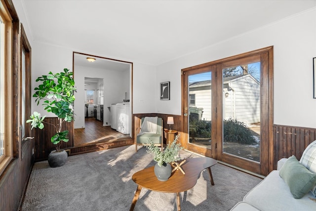 living room featuring crown molding, independent washer and dryer, carpet, and wood walls