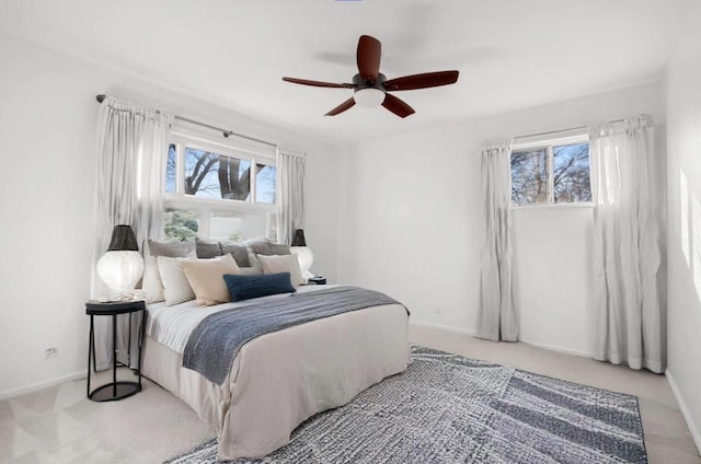 bedroom with ceiling fan, light carpet, and multiple windows