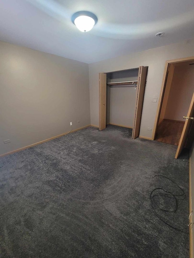 unfurnished bedroom featuring a closet and dark carpet