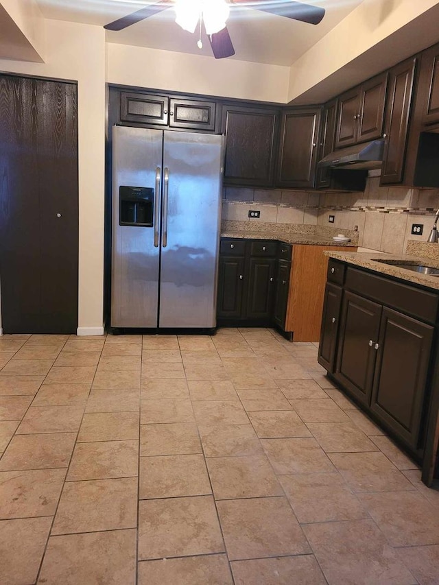 kitchen featuring light stone countertops, stainless steel refrigerator with ice dispenser, dark brown cabinets, and sink