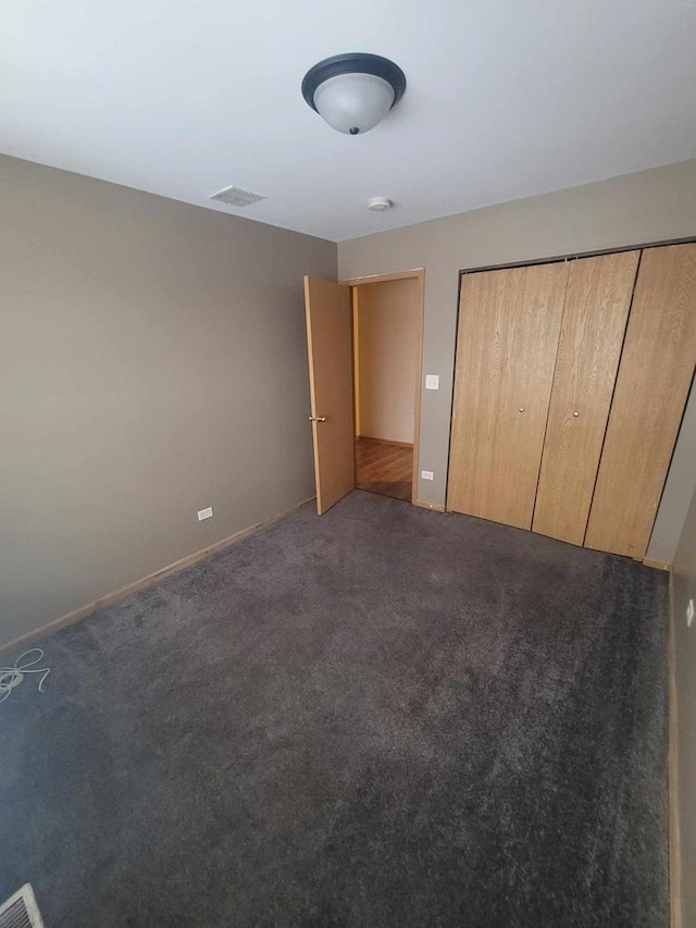 unfurnished bedroom featuring dark colored carpet and a closet