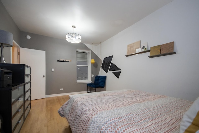 bedroom with a notable chandelier and light wood-type flooring