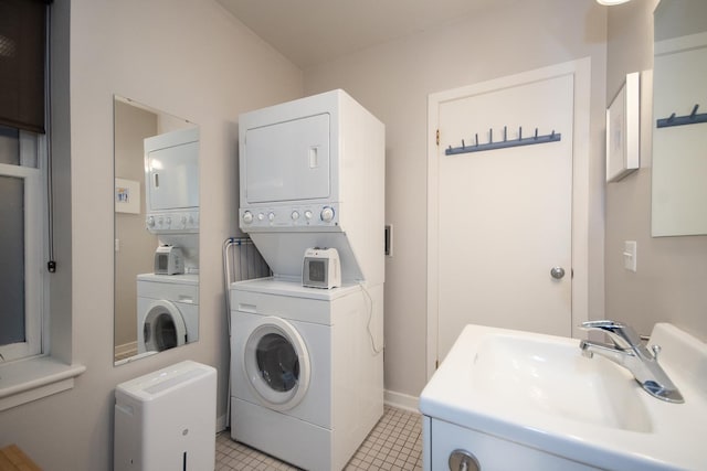 clothes washing area featuring light tile patterned flooring, stacked washing maching and dryer, and sink