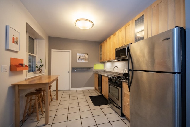 kitchen with backsplash, stainless steel appliances, sink, light brown cabinets, and light tile patterned floors