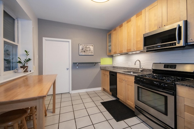 kitchen with sink, light tile patterned floors, light brown cabinets, and appliances with stainless steel finishes