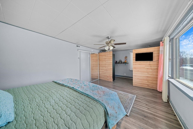 bedroom with baseboards, visible vents, ceiling fan, and wood finished floors