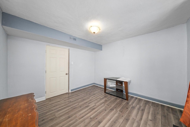 interior space featuring visible vents, a textured ceiling, baseboards, and wood finished floors