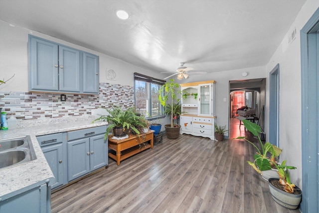 kitchen with blue cabinets, light countertops, light wood-style floors, and tasteful backsplash