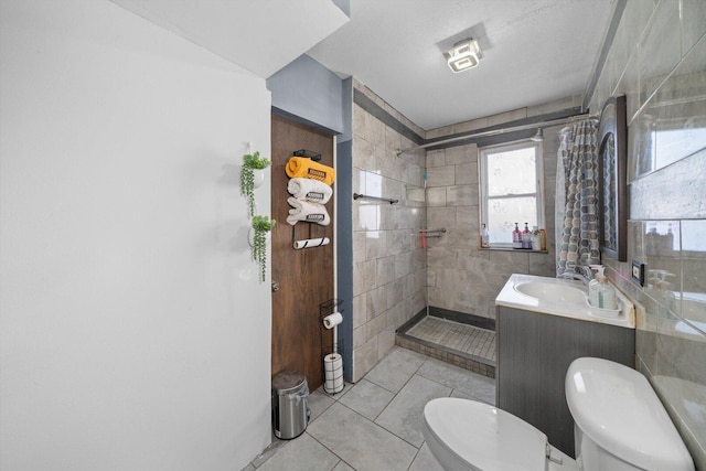 bathroom featuring a tile shower, vanity, toilet, and tile patterned floors