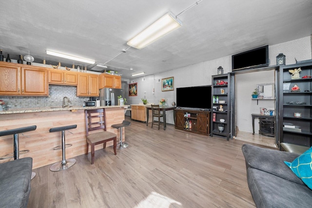 kitchen featuring light wood-type flooring, open floor plan, and stainless steel fridge