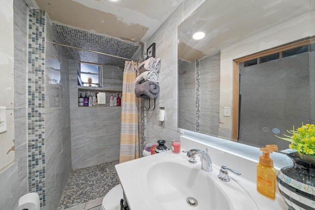 bathroom featuring a sink, tile walls, toilet, and tiled shower