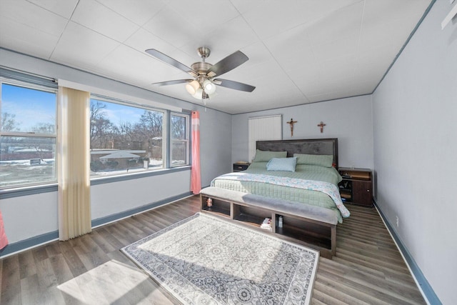 bedroom featuring multiple windows, baseboards, and wood finished floors