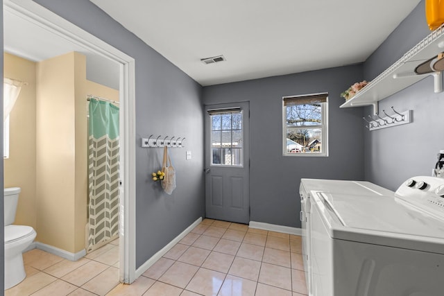 laundry area featuring washing machine and dryer and light tile patterned floors