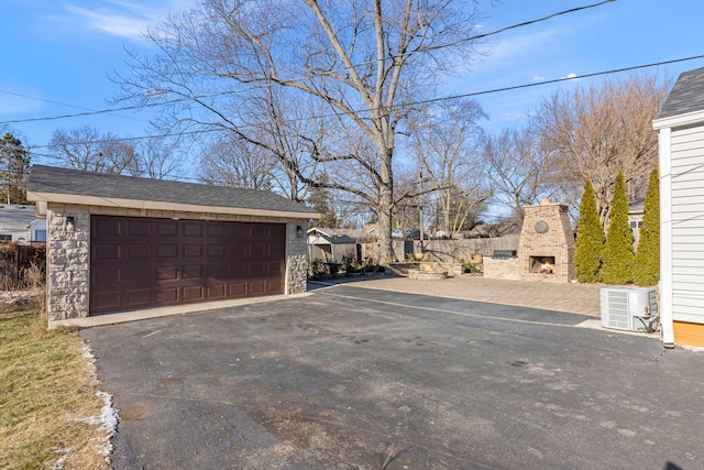 garage featuring central AC unit and an outdoor stone fireplace