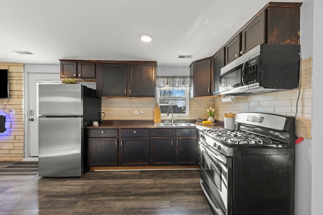 kitchen featuring dark brown cabinets, stainless steel appliances, dark wood-type flooring, and sink