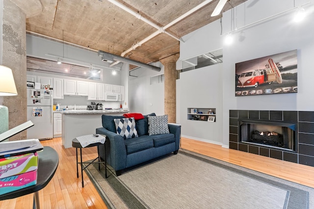 living room featuring track lighting, light wood-type flooring, and a tiled fireplace