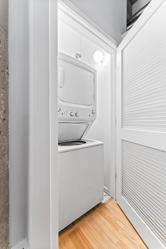 laundry room featuring hardwood / wood-style floors and stacked washer / dryer