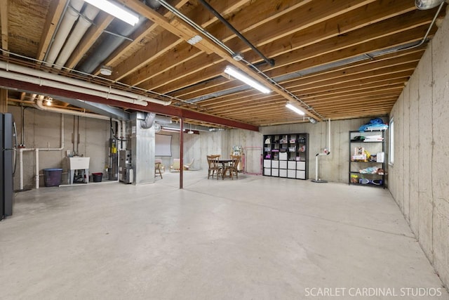 basement with black fridge, sink, and heating unit