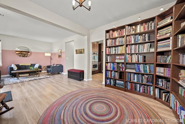 living area with beamed ceiling, light wood-type flooring, and a notable chandelier