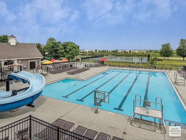 view of pool with a water slide and a patio area