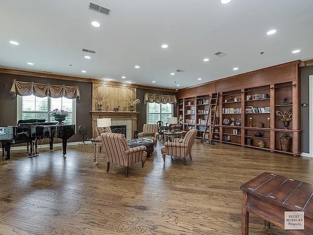 living room with crown molding, a large fireplace, hardwood / wood-style floors, and a wealth of natural light