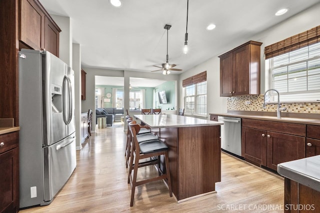 kitchen featuring sink, a breakfast bar, backsplash, stainless steel appliances, and a center island