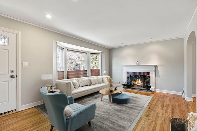 living room featuring light hardwood / wood-style flooring, crown molding, and a fireplace