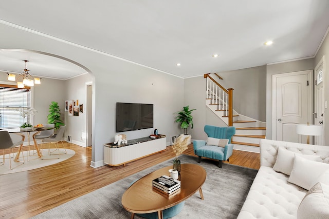 living room featuring wood-type flooring, crown molding, and an inviting chandelier