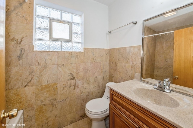 bathroom with a shower, vanity, tile walls, and toilet