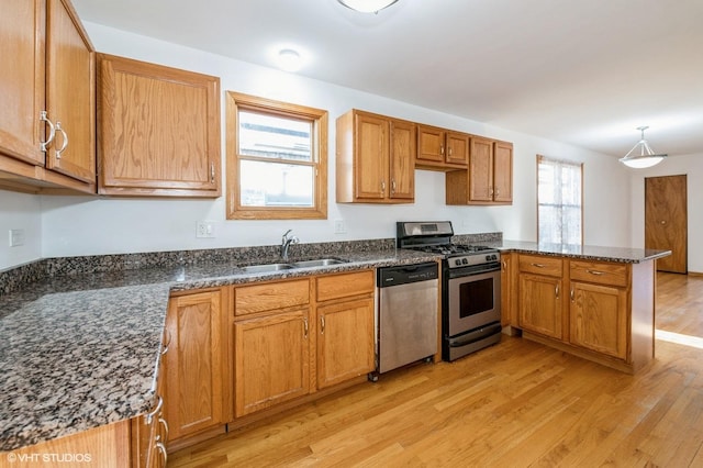 kitchen featuring appliances with stainless steel finishes, a healthy amount of sunlight, sink, light hardwood / wood-style flooring, and hanging light fixtures