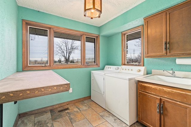 laundry area featuring sink, cabinets, washer and dryer, and a textured ceiling