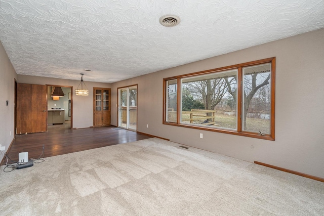 unfurnished living room featuring carpet flooring and a textured ceiling