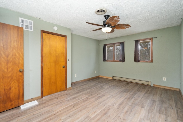 unfurnished room featuring ceiling fan, a baseboard heating unit, a textured ceiling, and light hardwood / wood-style floors