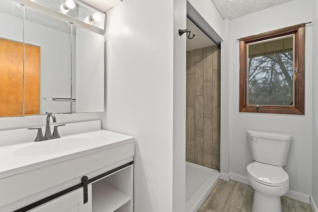 bathroom featuring vanity, toilet, wood-type flooring, and a tile shower