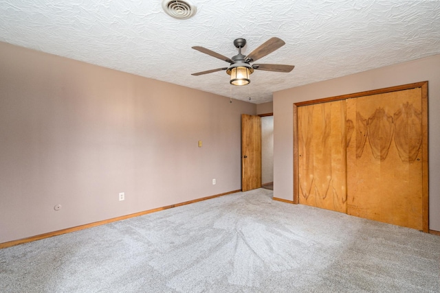 unfurnished bedroom featuring ceiling fan, carpet floors, a closet, and a textured ceiling