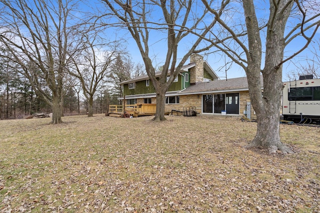 rear view of property featuring a lawn and a deck