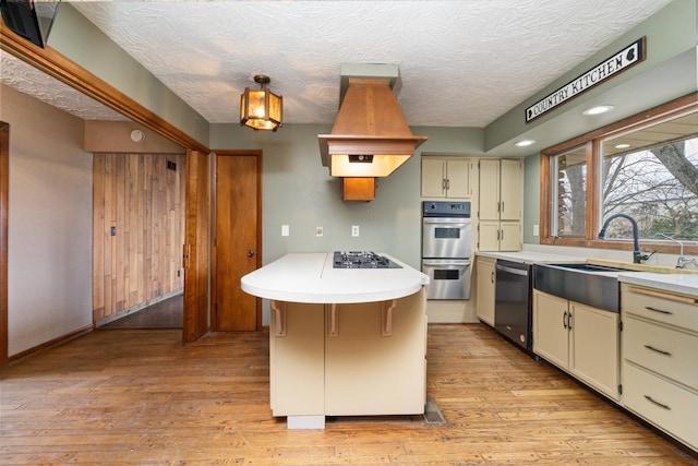 kitchen featuring black appliances, sink, light hardwood / wood-style flooring, and decorative light fixtures