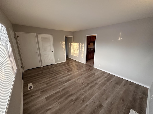 unfurnished bedroom with dark hardwood / wood-style floors and ensuite bath